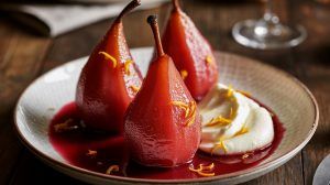 a plate of 3 red wine poached pears with a dollop of mascarpone and seated in a rich red sauce