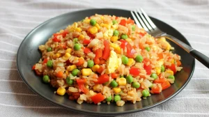  a colorful vegetable fried rice served on a matte black ceramic plate