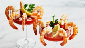 two elegantly presented shrimp cocktails in delicate coupe glasses atop a pristine white marble surface
