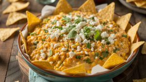 a bowl of Mexican street corn dip topped with feta cheese and lined with tortilla chips
