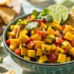 a bowl of colorful mango salsa with chips