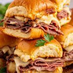 a platter of French dip slider sandwiches with a bowl of au jus