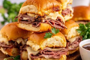 a platter of French dip slider sandwiches with a bowl of au jus