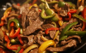 beef steak fajitas in a sizzling skillet with sliced onion and bell peppers